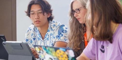 two students study with a faculty member